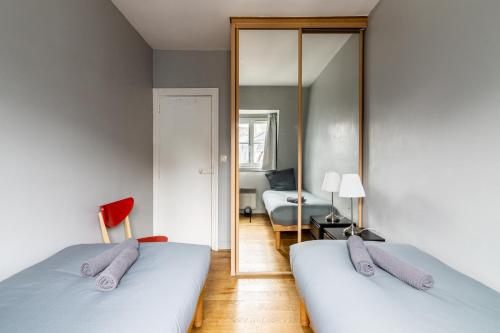 een slaapkamer met 2 bedden en een spiegel bij Luxurious 2 Bedroom Tour Eiffel Bourdonnais Free Netflix in Parijs