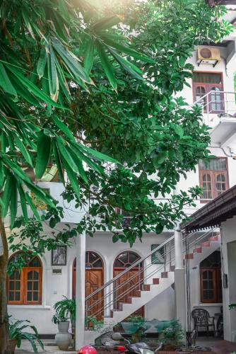 a white building with a staircase in front of a tree at SAKURAHANA VILLA AND AYURVEDA in Aluthgama