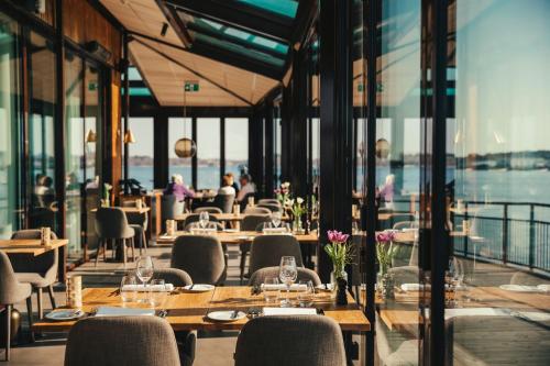 a restaurant with tables and chairs and windows at Slottsholmen Hotell och Restaurang in Västervik