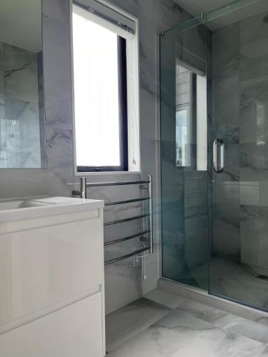 a bathroom with a glass shower and a sink at Relax by the Tamaki River in Auckland