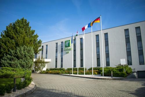 een gebouw met twee vlaggen ervoor bij Holiday Inn Budapest-Budaörs, an IHG Hotel in Budaörs