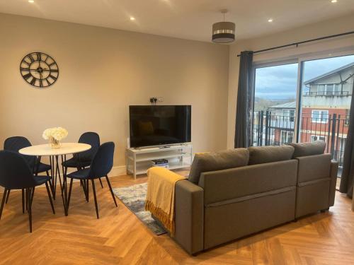 a living room with a couch and a tv and a table at New build 1 bedroom modern apartment Rickmansworth in Rickmansworth