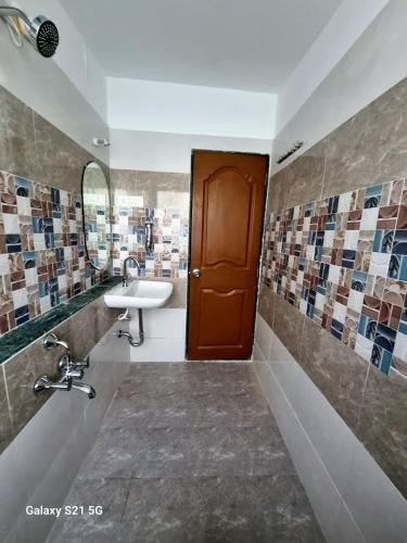 a bathroom with a sink and a brown door at JOY HOSTEL - Digital Nomads Hostel & PG - Koregaon Park in Pune