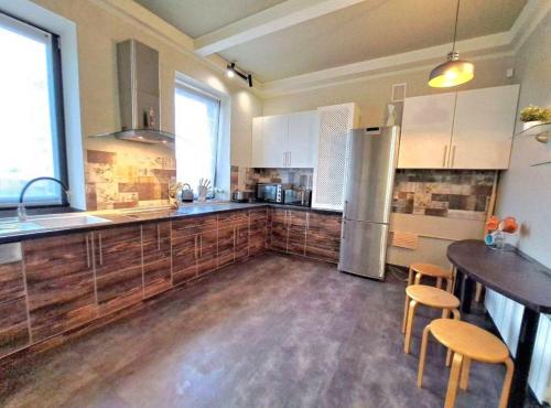 a large kitchen with wooden floors and a stainless steel refrigerator at Пентхаус с террасой. Апартаменты в центре in Kharkiv