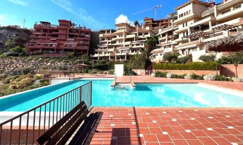 a swimming pool in front of a large building at Apartamento Isla del Fraile in Águilas
