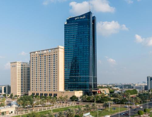 Ein hohes Gebäude mit einem Schild in einer Stadt. in der Unterkunft Dusit Thani Abu Dhabi in Abu Dhabi