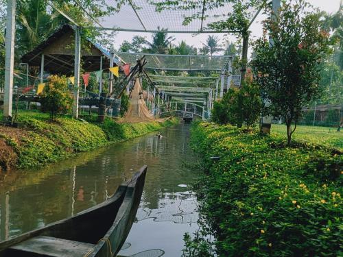 a boat in a river with a bridge over it at Village of Blossom in Ernakulam