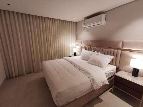 a bedroom with a large bed with white sheets at شقة فاخرة بالقرب من البوليفارد A13 in Riyadh