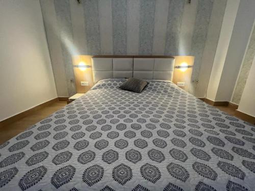 um quarto com uma cama grande e um edredão preto e branco em appartement haut standing em Agadir