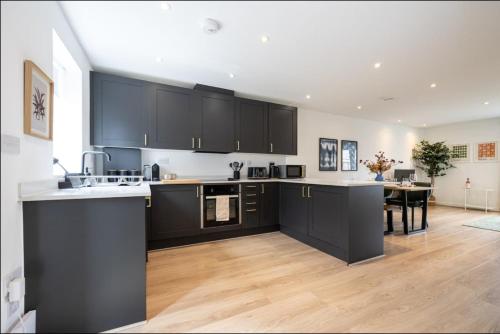a kitchen with black cabinets and a dining room at Luxury 2 Bed Holiday Home With Parking in Manchester