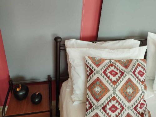 a bed with white pillows and a red wall at Nest & nook in Chios