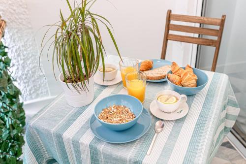 una mesa cubierta con tazones de alimentos para el desayuno y zumo de naranja en Nuevo apartamento de lujo Centro y playa, en Torremolinos