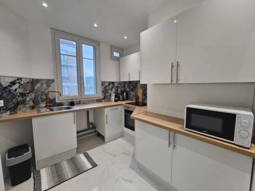 a kitchen with white cabinets and a sink and a microwave at Magnifique Appartement Clichy in Clichy
