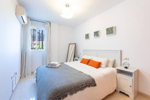 a white bedroom with a bed with orange pillows at Estupendo apartamento junto a magníficas playas in Torremolinos
