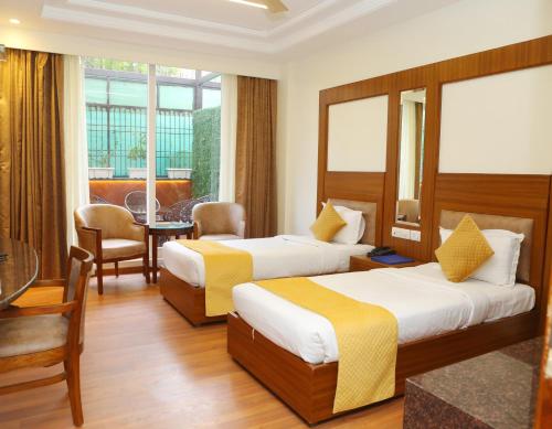 um quarto de hotel com duas camas e uma mesa e cadeiras em Karon Hotels - Lajpat Nagar em Nova Deli