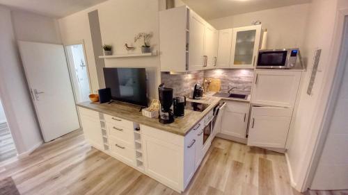 eine Küche mit weißen Schränken und Holzböden in der Unterkunft Ferienpark - Haus N, App 0N0502 in Heiligenhafen