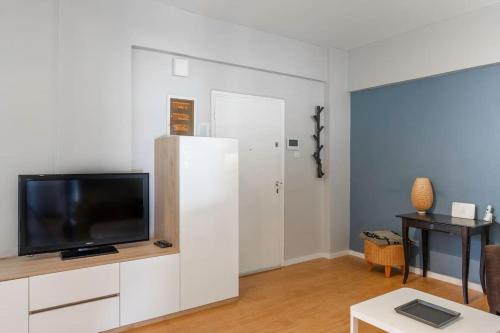 a living room with a tv and a white refrigerator at Simplicity and Comfort: Apartment in Zografou in Athens