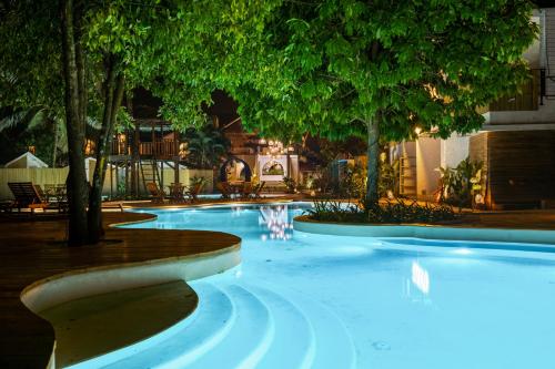 a swimming pool at night with trees and lights at Azora by Ayatana, Goa in Morjim