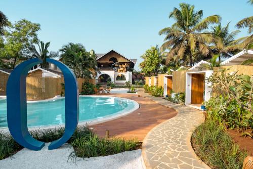 a villa with a swimming pool in front of a house at Azora by Ayatana, Goa in Morjim