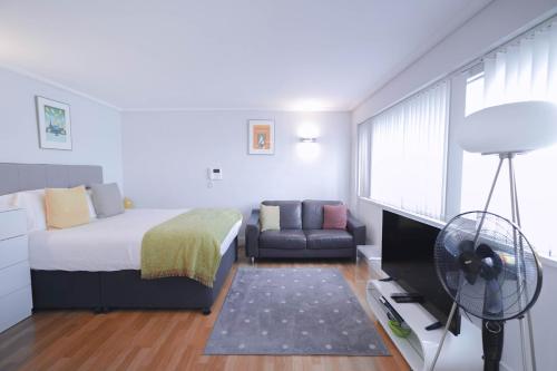 1 dormitorio con cama, sofá y ventilador en Camden Serviced Apartments by Globe Apartments, en Londres