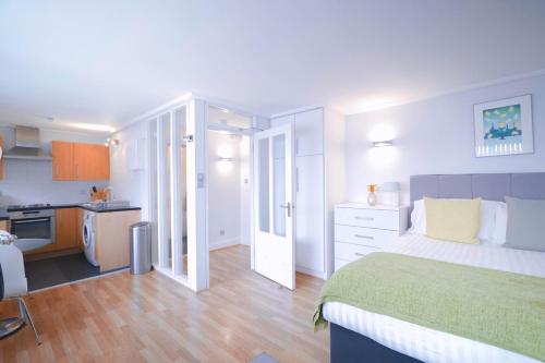 a bedroom with a large bed and a kitchen at Camden Serviced Apartments by Globe Apartments in London