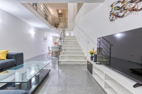 ein Wohnzimmer mit einer Couch und einem Fernseher und Treppen in der Unterkunft An amazing 2BR home with a special private rooftop by 360 Estates in Sliema