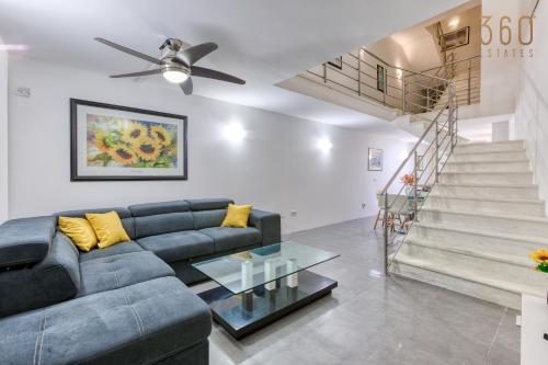 ein Wohnzimmer mit einem blauen Sofa und einer Treppe in der Unterkunft An amazing 2BR home with a special private rooftop by 360 Estates in Sliema