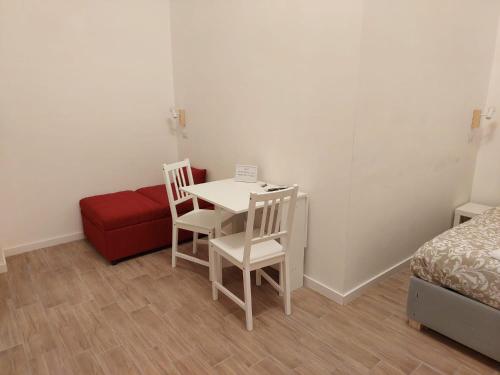una camera con tavolo, sedie e divano rosso di Residence e Appartamenti Ascensione a Napoli