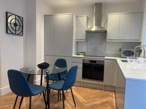 a kitchen with a glass table and blue chairs at New 2 Bedroom Apartment Rickmansworth Town Centre in Rickmansworth
