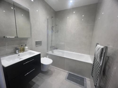 a bathroom with a tub and a toilet and a sink at New 2 Bedroom Apartment Rickmansworth Town Centre in Rickmansworth
