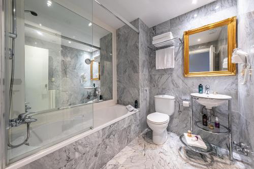 a bathroom with a tub and a toilet and a sink at Hotel Caribou in Pas de la Casa