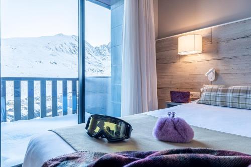 a hotel room with a bed with a view of snow covered mountains at Hotel Caribou in Pas de la Casa