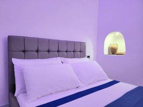 una camera da letto con un grande letto con cuscini bianchi di Anim Suite nel cuore di Ercolano a Ercolano