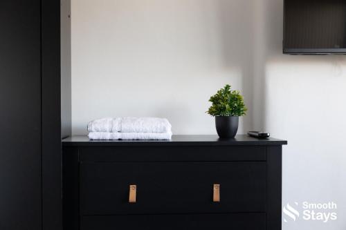 a black dresser with a plant on top of it at Modern 2 Bed House With Driveway in Longton