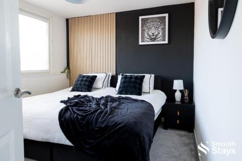 a bedroom with a large bed with black walls at Modern 2 Bed House With Driveway in Longton