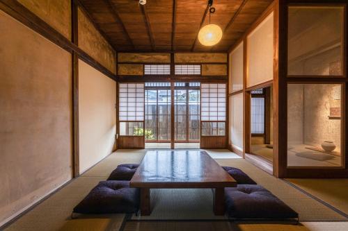 a room with a wooden table and some windows at NIPPONIA HOTEL Ozu Castle Town in Ōzu