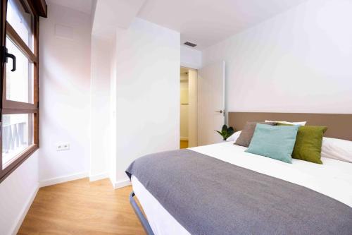 a bedroom with a large white bed with green pillows at Apartamentos turísticos Plaza Sevillano , by CartagenaSpain in Cartagena