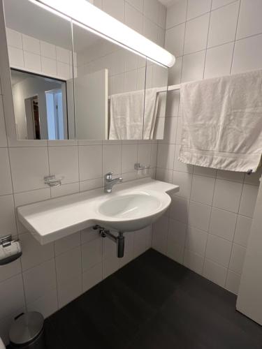 Baño blanco con lavabo y espejo en Privat Bed and Breakfast in Flims Waldhaus, en Flims