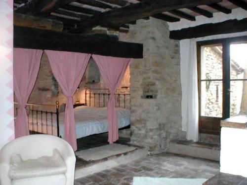 a bedroom with a bed with pink curtains and a chair at Antico-Borgo-Le-Torricelle-Kleines-Haus in Piandimeleto