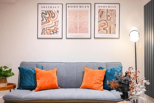 a living room with a blue couch with orange pillows at Luxury 2 Bed Maisonette with Parking Near Tube in London