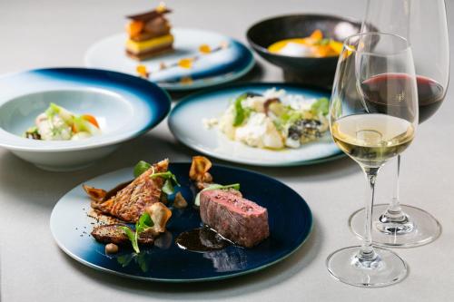 a table with plates of food and a glass of wine at NIPPONIA HOTEL Ozu Castle Town in Ōzu