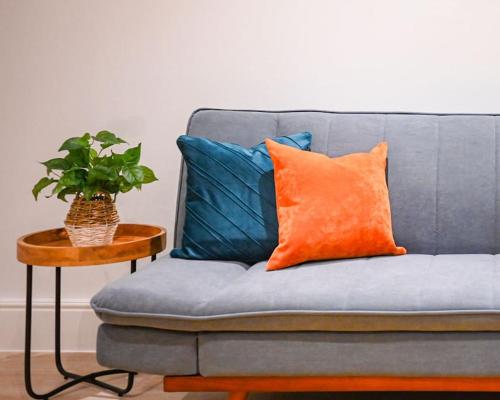- un canapé bleu avec un oreiller orange et une table dans l'établissement Luxury 2 Bed Split Level Maisonette W/Parking, à Londres