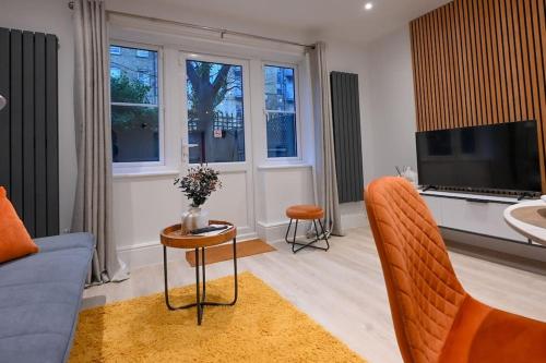 a living room with a couch and a tv at Luxury 2 Bed Maisonette with Parking Near Tube in London