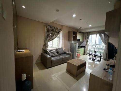 een woonkamer met een bank en een tafel bij Madison Park Apartment Near Mall Central Park in Jakarta