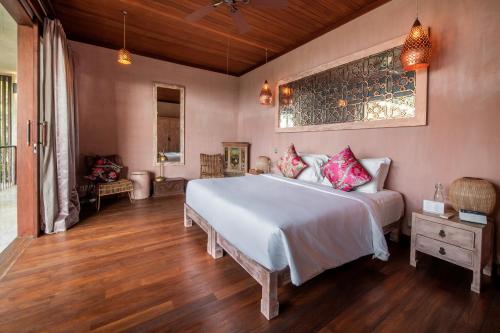 a bedroom with a large white bed and wooden floors at Villa Manis Beachfront Candidasa in Candidasa