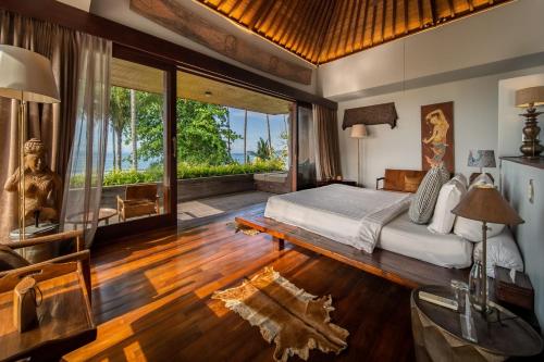a bedroom with a bed and a large window at Villa Manis Beachfront Candidasa in Candidasa