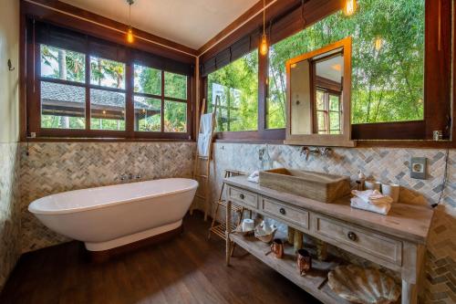 a bathroom with a tub and a sink and a mirror at Villa Manis Beachfront Candidasa in Candidasa