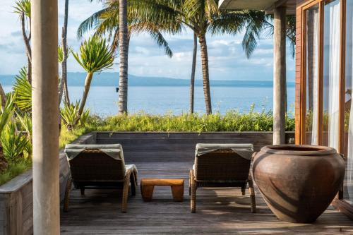 a porch with two chairs and a large vase at Villa Manis Beachfront Candidasa in Candidasa