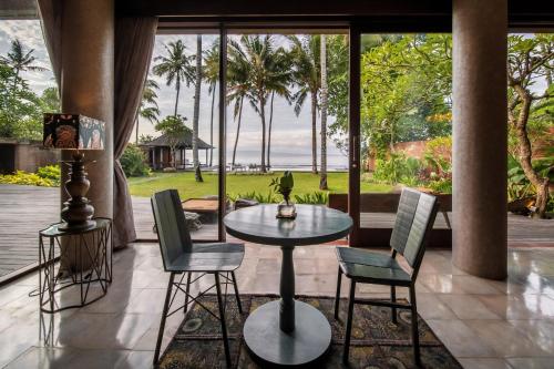 patio ze stołem i krzesłami oraz widokiem na ocean w obiekcie Villa Manis Beachfront Candidasa w mieście Candidasa