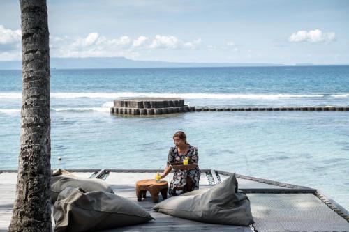 a woman sitting on a table next to the ocean at Villa Manis Beachfront Candidasa in Candidasa
